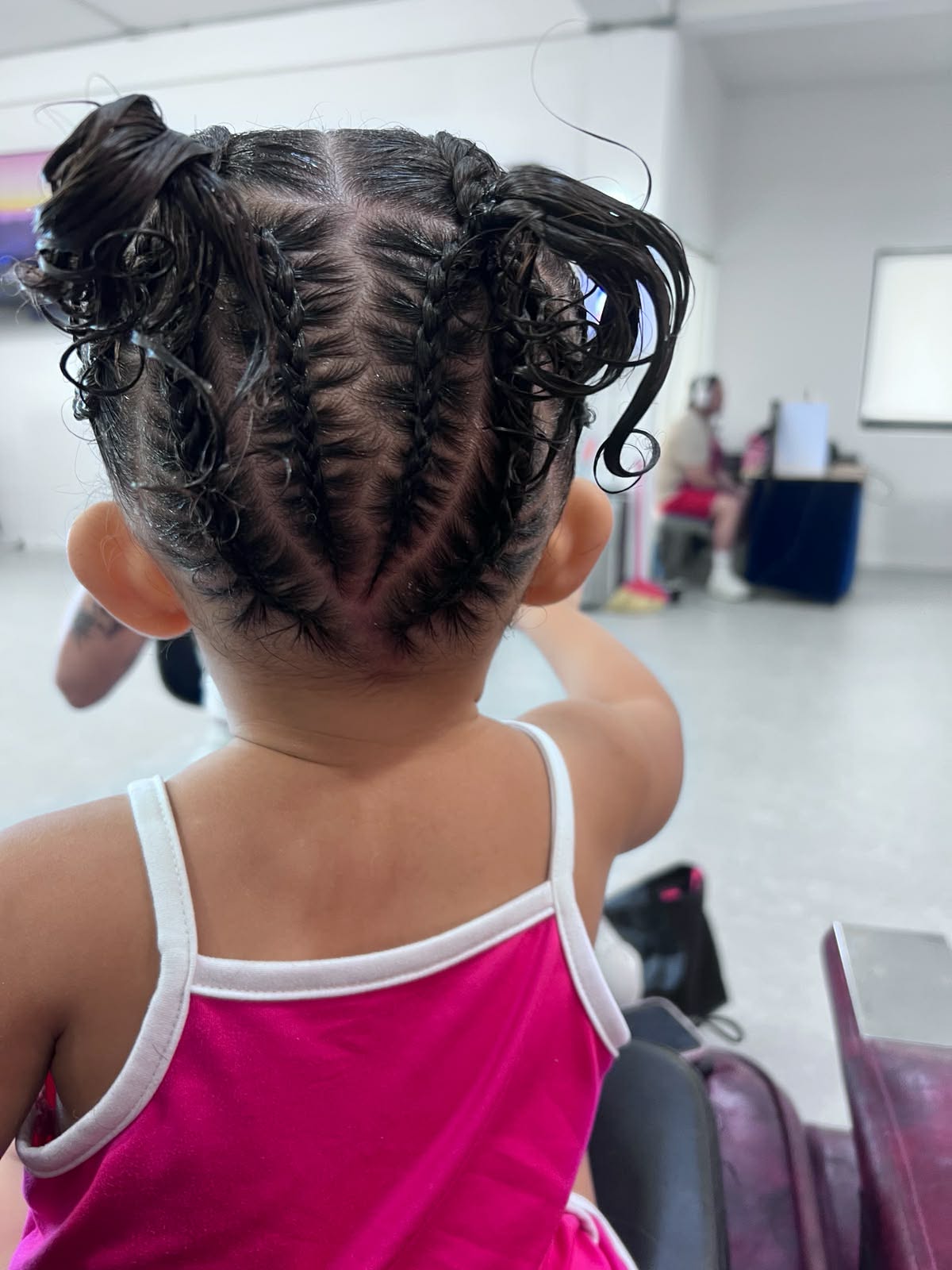 Stitch braids into two curly pigtails on a toddler