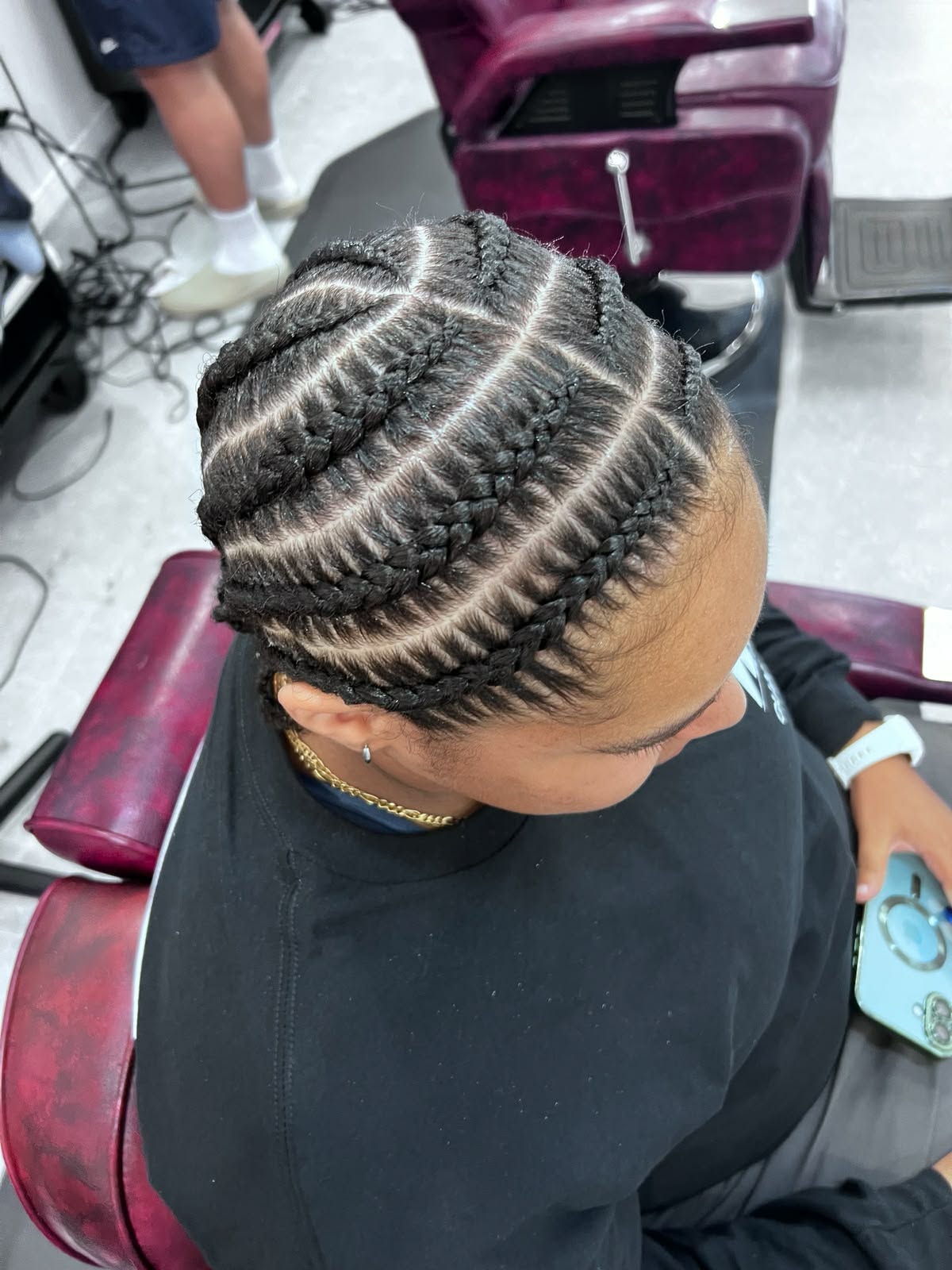 Large curved cornrows with a clean part on a male client